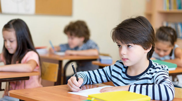 Bambini in aula mentre prendono appunti sui fogli durante una lezione