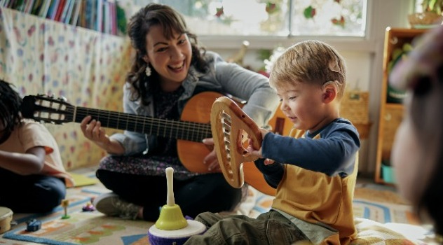 bambino con impianto cocleare che suona uno strumento e gioca con la mamma che sorride e suona la chitarra