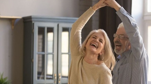Una coppia di adulti mentre balla e sorride in casa
