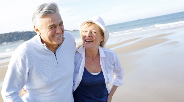 Coppia di persone adulte sorridenti mentre passeggia in riva al mare