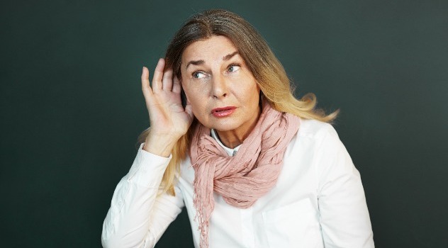 Donna adulta con la mano posizionata vicino all'orecchio che sta cercando di sentire meglio.