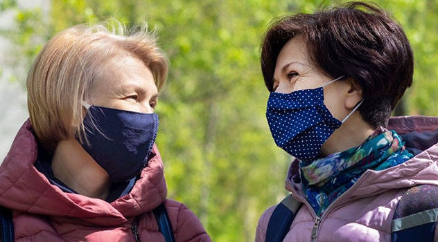 Due donne che parlano e sorridono indossando una mascherina