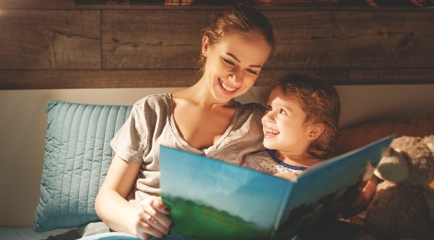 Giovane mamma mentre legge una fiaba alla figlia