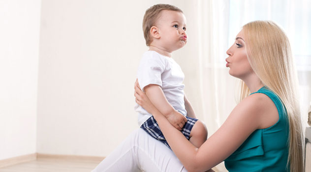 Una madre che parla a suo figlio piccolo mentre fa una smorfia con le labbra