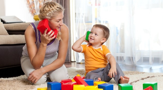 Mamma e figlio che giocano facendo finta di parlarsi attraverso telefoni giocattolo