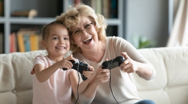 Nonna sorridente che gioca ai videogame insieme alla sua nipotina