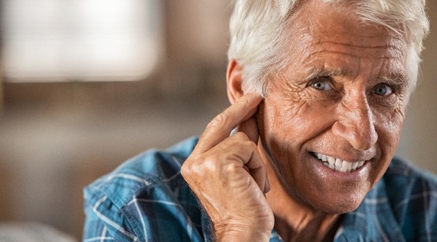 Persona anziana sorridente che si tocca in prossimità dell'orecchio