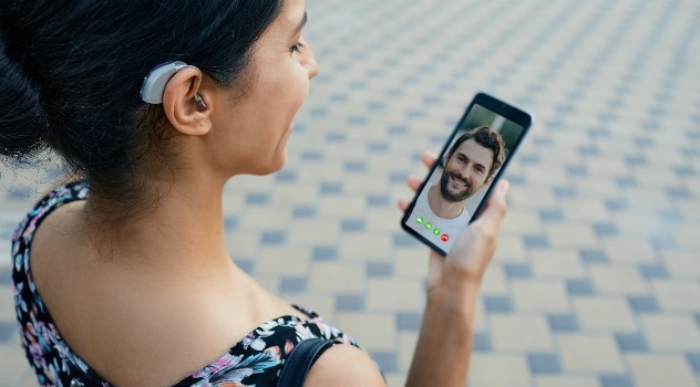 Ragazza che indossa un apparecchio acustico mentre parla in videochiamata con un ragazzo