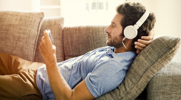 Ragazzo steso sul divano che ascolta la musica con le cuffie