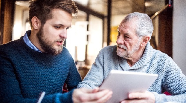 Un ragazzo che parla con suo padre mentre insieme mantengono un tablet