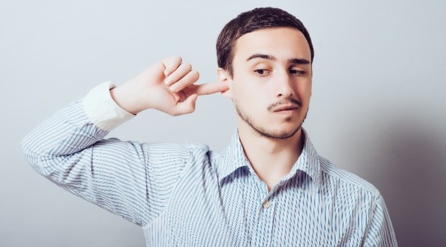 Ragazzo che si tocca l'interno dell'orecchio destro con l'indice