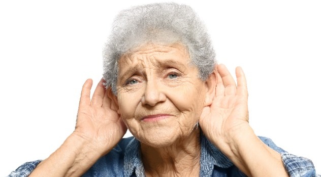 Signora anziana con le mani vicino alle orecchie per cercare di sentire meglio