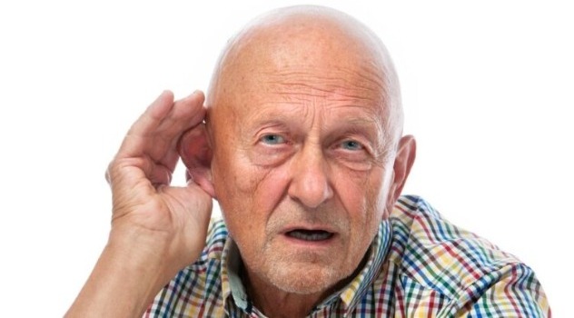 Un signore anziano senza capelli con la mano vicino all'orecchio sinistro per sentire meglio