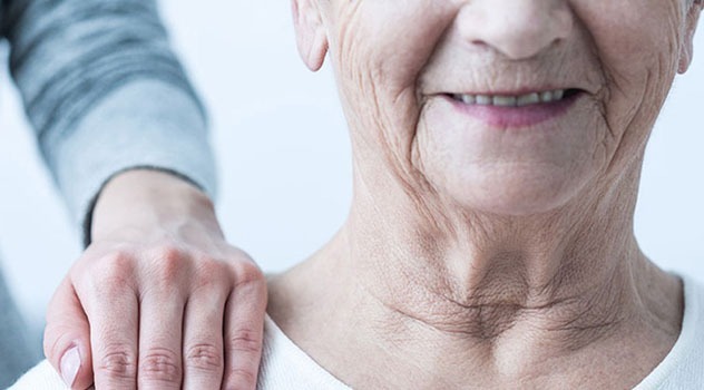 Il sorriso di una signora anziana mentre la mano di un&#039;altra persona è poggiata sulla sua spalla