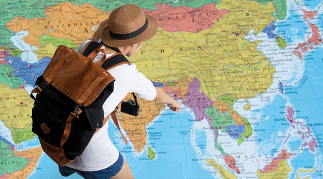 Una ragazza con zaino alle spalle che indica una località su una cartina geografica