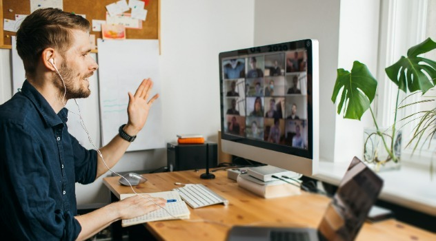 Uomo che indossa cuffie impegnato in una video call con tante persone.